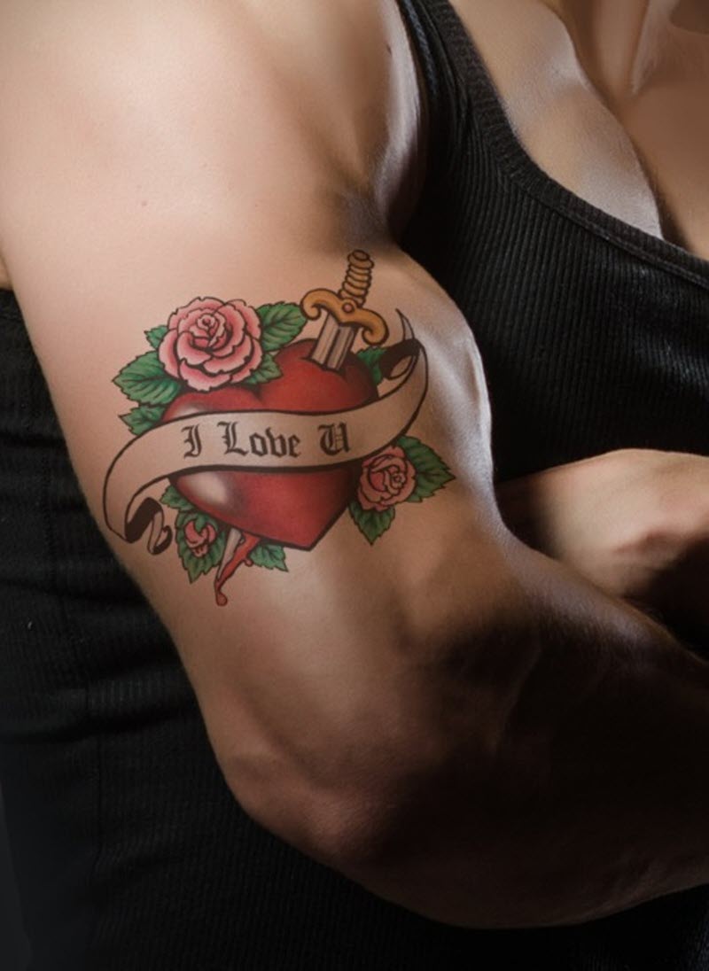 A man's arm with a tattoo of a heart with roses and a sword. The heart is red, the roses are pink and yellow, and the sword is silver. 